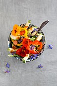 Pepper and courgette salad with nasturtium flowers, borage flowers, rosemary and chilli