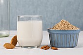 A glass of almond milk with whole and grated almonds