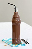 A small bottle of chocolate soya milk with a straw