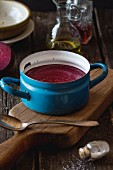 Cream of beetroot soup in an old pot on a wooden board