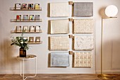Side table below postcards on narrow shelves and sheets of wrapping paper hung from rods next to elegant standard lamp
