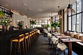 Restaurant mit Bar und Essplätzen, Felle auf Klassikerstühlen und Pendelleuchten in skandinavischem Design