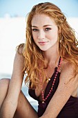 A young woman on a beach wearing a dark red bathing suit