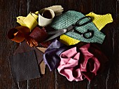 Scissors on pile of various fabric and leather remnants on wooden surface