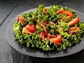 A mixed leaf salad with bacon and tomatoes