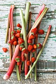 Rhubarb spears and strawberries on a wooden table (seen from above)