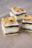 Three slices of almond cream cake with blackcurrant jam and flaked almonds