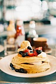 Pancakes with blueberries, strawberries, maple syrup and butter (USA)