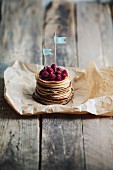 A stack of mini pancakes with raspberries and little flags