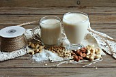 Two glasses of vegan milk, nuts, soya beans and oats