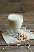 A glass of soya milk with soya beans next to it