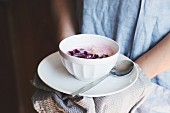 A person serving cold radish soup with red onions