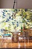 Dining table with various chairs in front of a jungle wallpaper