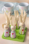 Cute, painted, wooden bunny ornaments with fabric ears on green wooden board with matching sockets