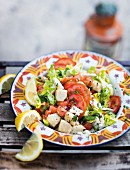Warm fish and potato salad with tomatoes, lemons and coriander