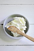 A bowl of cream cheese with a wooden spoon
