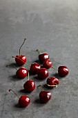 Red cherries scattered on a grey stone surface