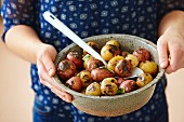 A woman holding a bowl of baby potatoes