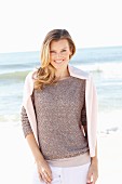 A young woman on a beach with a jumper over her shoulders