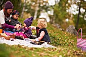 Mother and children enjoying an autumn woodland picnic