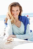 A young woman on a beach with a jumper over her shoulders