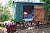 Vintage-style play house on cart and basket of flowering hydrangeas