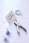 Craft materials for making place cards: punch pliers, flowers and masking tape