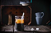 Tee mit Milch in Vintage-Teeglashalter auf rustikalem Holztisch