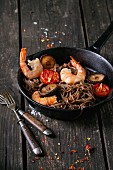 Prawns with soba noodles, mushrooms and tomatoes in a pan