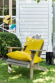 A wooden chair in a garden with a homemade cushion covers made from yellow raincoat material