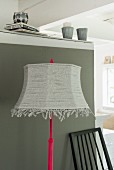 A floor lamp with a homemade lampshade made from strips of jersey