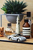 Various small bottles, succulents and model car on bathroom cabinet