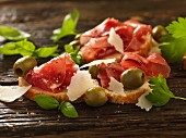 Bruschetta topped with Bresaola, green olives and Parmesan shavings