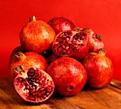 Pomegranates and two pomegranate halves against a red background