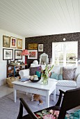 Sofa, white coffee table and wall covered in black and white wallpaper in romantic Swedish cabin