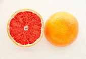 A halved pink grapefruit on a white surface