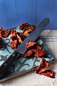 Dried tomatoes on a chopping board with a knife