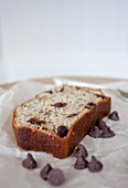 A slice of banana bread with chocolate chips on a piece of parchment paper