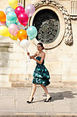 Junge Frau in Cocktailkleid mit vielen LuftballonsEin