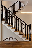 Elegant restaurierte Holztreppe mit schwarz lackiertem Geländer und indirekter Beleuchtung