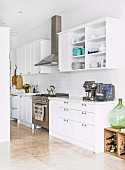White country-style fitted kitchen with stainless steel gas hob and extractor hood