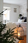 View into cosy bedroom with lit candle in floor lantern