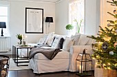 Fairy lights on Christmas tree in front of white sofa with many scatter cushions