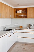 L-shaped kitchen counter with white worksurface and base units below solid wood wall units with one open-fronted unit
