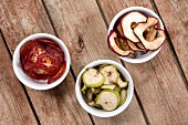Dried tomatoes, pears and apples in white bowls on a wooden table