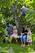 Family eating fruit tart under tree in garden