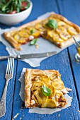 A puff pastry tart with yellow courgette, pesto rosso, cheese and basil