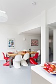 Essplatz mit farbigen Klassiker Schalenstühle um Tisch in hellem, offenem Wohnraum