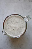 Fresh hemp milk made from roasted, organic hemp sees in a glass jug on a marble surface