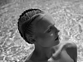 Young woman with elaborately braided hair in water (monochrome photo)